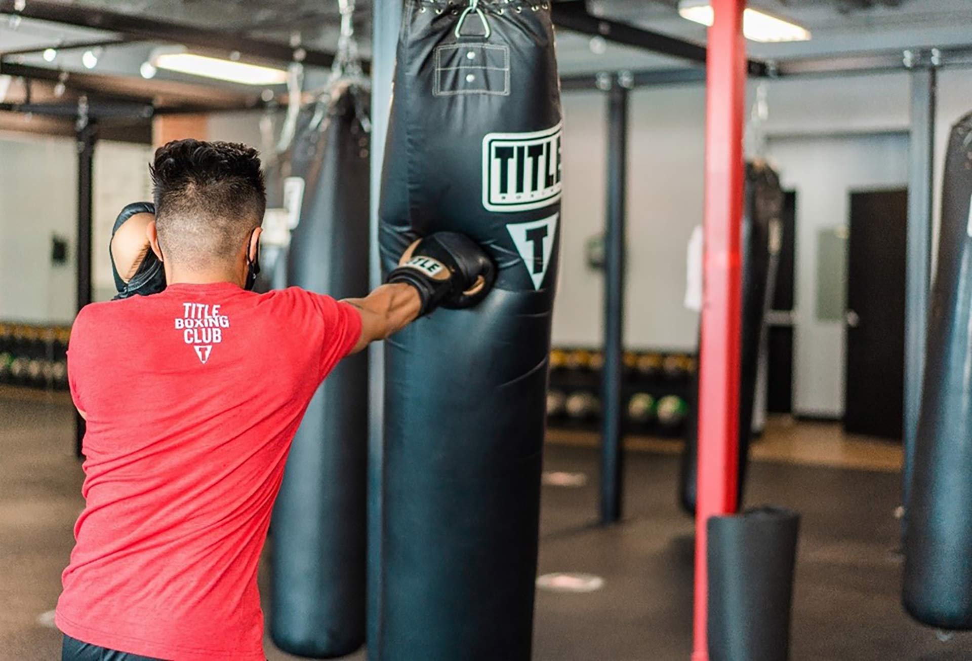 Man punching a heavy bag at TITLE Boxing Club