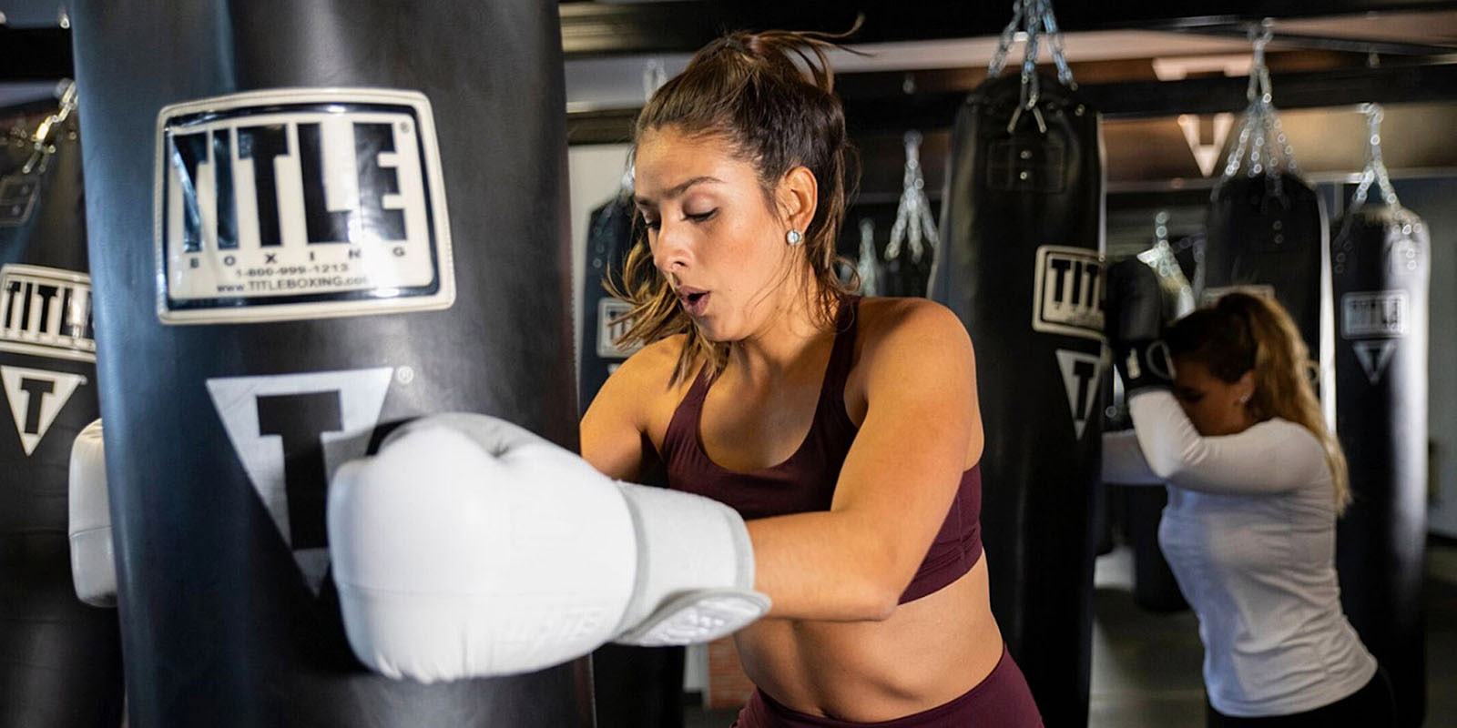 Woman kicking a heavy bag during a TITLE Boxing Club class