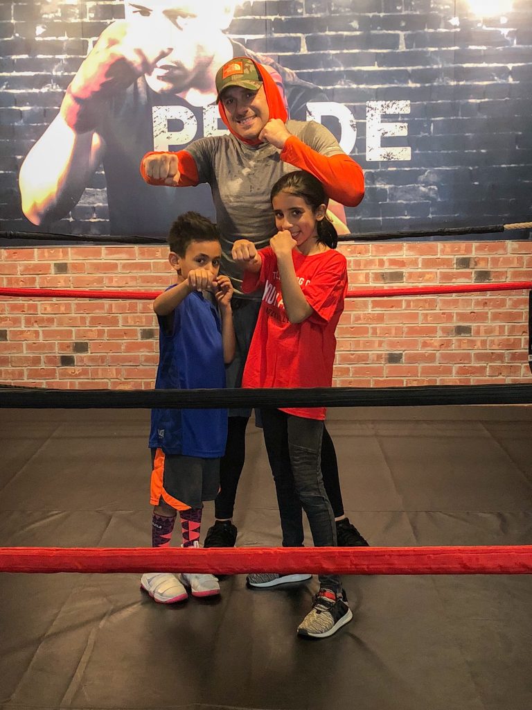 man and two kids with fists up in boxing ring