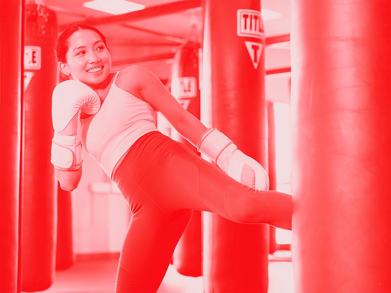 woman kicking weighted bag